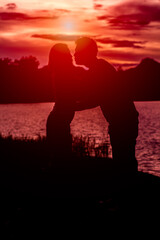silhouette of romantic lovers with river in thailand with sunset