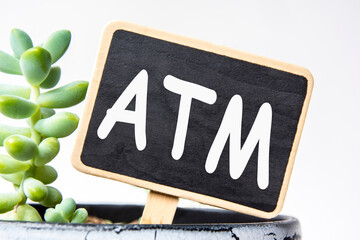 small black chalk board in a pot with succulents inscribed in white letters atm. business concept,...