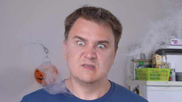 Young man is angry at someone and gestures with his head to indicate the direction, steam coming out of ears from rage. The concept of vivid expression of emotions.