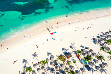 Aerial drone view of beautiful caribbean tropical beach with straw umbrellas, palms and boats. Bavaro, Punta Cana, Dominican Republic. Vacation background.