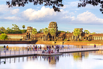 Naklejka premium turyści tłoczący się na kładce nad wodą przed świątynią Angkor wat, aby oglądać zachód słońca.