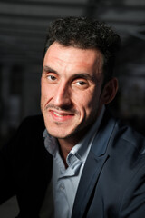 Obraz premium Close up portrait of a serious man 30-34 years old in a blue shirt and a dark jacket on a black background.