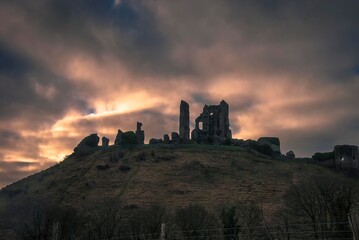 Obraz premium The sun rises behind the ruins of Corfe Castle in Dorset, UK