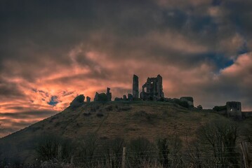 Obraz premium The sun rises behind the ruins of Corfe Castle in Dorset, UK