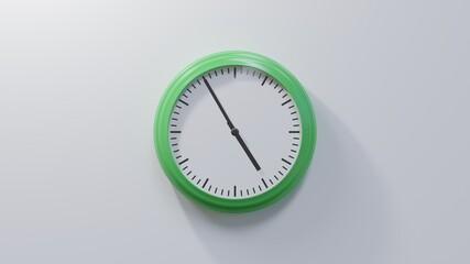 Glossy green clock on a white wall at five to five. Time is 04:55 or 16:55