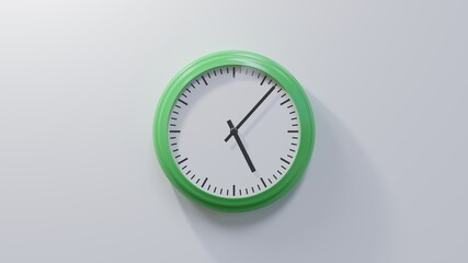 Glossy green clock on a white wall at seven past five. Time is 05:07 or 17:07