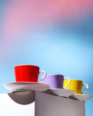 Violet, Yellow and red cup for coffee stand on a white cube