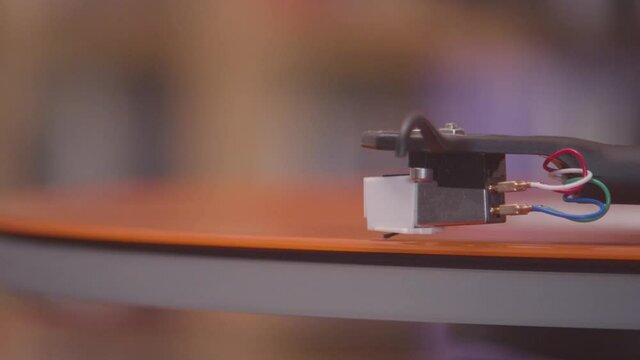 Spinning and lifting stylus off of an orange vinyl lp extreme close up