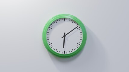 Glossy green clock on a white wall at nine past six. Time is 06:09 or 18:09