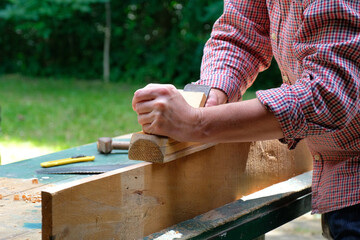 Craftswoman working with planer outdoors, close-up view. Woodworking, furniture production, carpentry concept.