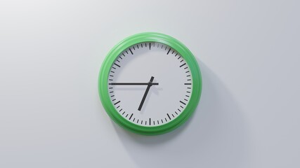 Glossy green clock on a white wall at quarter to seven. Time is 06:45 or 18:45