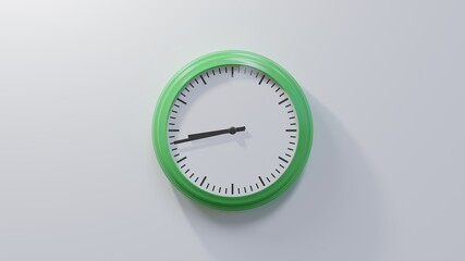 Glossy green clock on a white wall at forty-three past eight. Time is 08:43 or 20:43