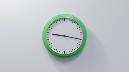 Glossy green clock on a white wall at seventeen past nine. Time is 09:17 or 21:17