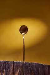 Golden Spoon standing on wooden frame. yellow background