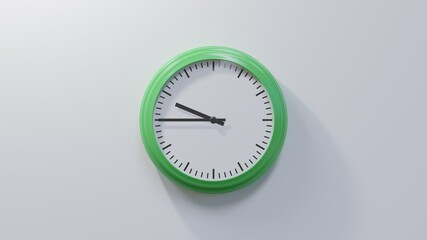 Glossy green clock on a white wall at quarter to ten. Time is 09:45 or 21:45