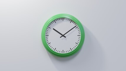 Glossy green clock on a white wall at nine past ten. Time is 10:09 or 22:09