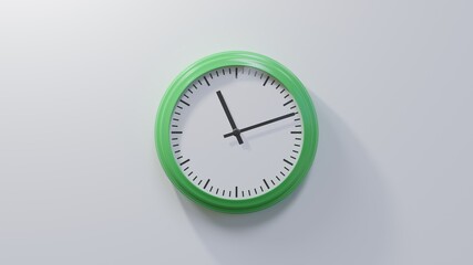 Glossy green clock on a white wall at twelve past eleven. Time is 11:12 or 23:12