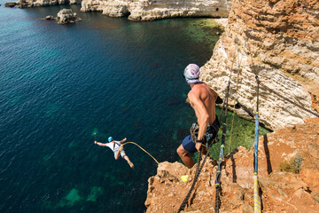 Rope jumping off a cliff with a rope in the water. The ocean. Sea. Mountain.