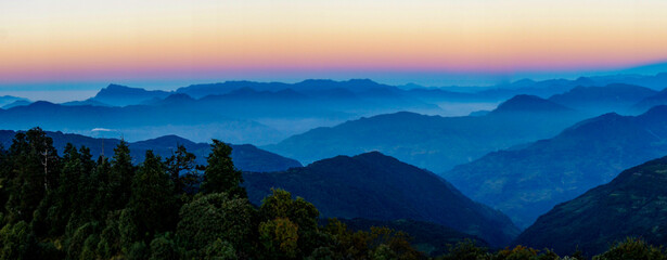 Mountain landscape in the evening light. Nepalese blue mountain silhouettes at pink sunset. Panorama