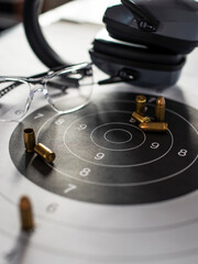 Shooting target with ammunition, pistol, ballistic glasses and headphones