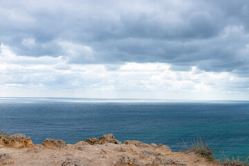 Fototapeta na wymiar stone ledge into the sea. Calm blue sea and sky with clouds. Travel, relax or loneliness concept
