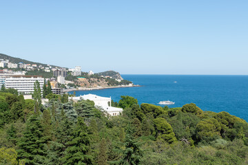Fototapeta na wymiar Beautiful view of the city near the Black Sea coast on a sunny day. Seascape at the Southern coast of Crimea (Yalta, Miskhor). Summer vacation concept.