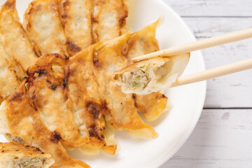 白い木目背景の白い皿にのせた餃子