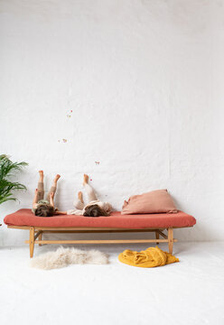 Zwei Kinder liegen auf Bett im sch&ouml;n gestalteten Kinderzimmer und haben Spa&szlig;, strecken ihre F&uuml;&szlig;e die Wand hoch 