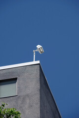 Low angle view of the roof corner of a professional building under blue sky with a flood light lamp installed on top