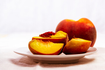 still life with fresh ripe seasonal peaches on white rustic tablecloth