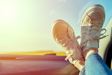 Woman feet in sneakers on car dashboard. Roadtrip and freedom travel concept