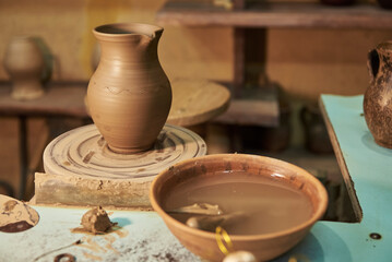 Clay pot on potter's wheel in workshop interior