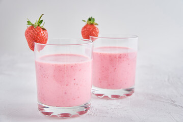Two glasses with strawberry shake on white background