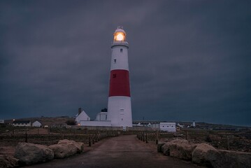 Fototapeta na wymiar Portland Bill lighthouse on the south coast of England in Dorset shines out against a background of dark clouds