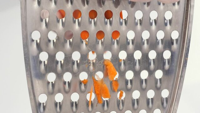 A hand grating a carrot on a grater