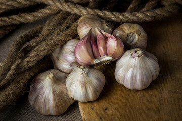 Garlic. A bunch of garlic lies on a wooden cutting board. Jute rope in the background. Agriculture concept