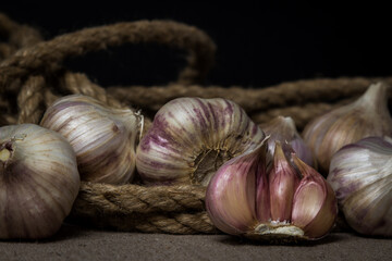 Garlic lies in a jute rope on a sacking. Half garlic among whole garlic. Agriculture concept