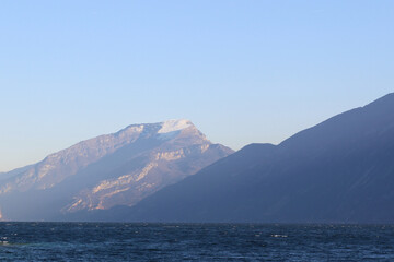 travel to snowy mountains in Italy, beautiful italian mountains neighboring lake Garda, lake along with mountains and blue sky, beautiful italian landscape with mountains