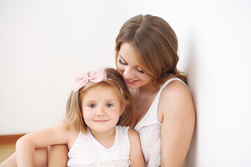 Mother and daughter play hugging lying on the floor in the room