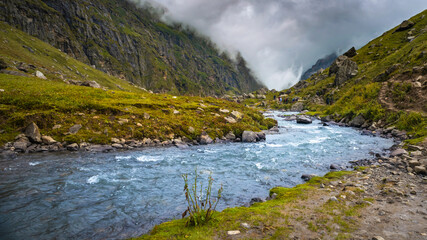 stream in the mountains. The beautiful stream flowing among the litigants, flowing in Parvati valley on a trek to Hamta Pass, 4270 m on the Pir Panjal range in the Himalayas.