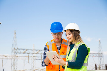 Young workers looking and checking wind turbines at field