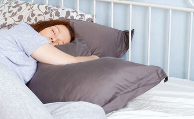 Young woman lies in bed with closed eyes. Morning at home. Lockdown authenticity.