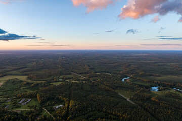 Beautiful sunset over the small town. Fields and trees around. Aerial photography.