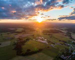Beautiful sunset over the small town. Fields and trees around. Aerial photography.