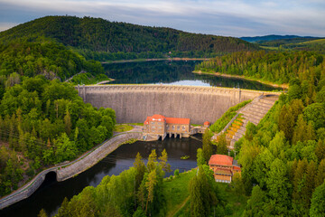 Water turbines are producing clean electricity at power plant in Pilchowice power plant. River dam and mountains. Drone shot of stone dam at reservoir, hydroelectricity power station