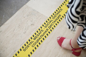 Store or hotel markings on the floor, keep a social distance at least 1,5 meters. a woman stands near a marking on the floor,woman standing on a chekout counter with sign multi language