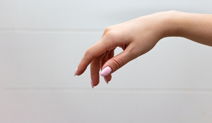 A well-groomed female hand with a neat manicure hanging smoothly in the air on a light background.