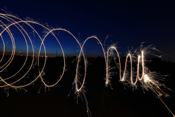 spiral of light in the field during sunset with the moon in the sky and the colors red and blue on the horizon