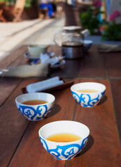 three pialas with tea on the wooden table of the restaurant on outdoor in the shining day