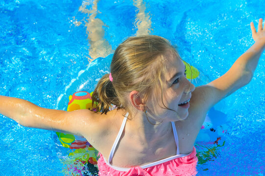 closeup - a beautiful girl of ten years old, smiling, swims on an inflatable ring in the pool at home on a hot summer day